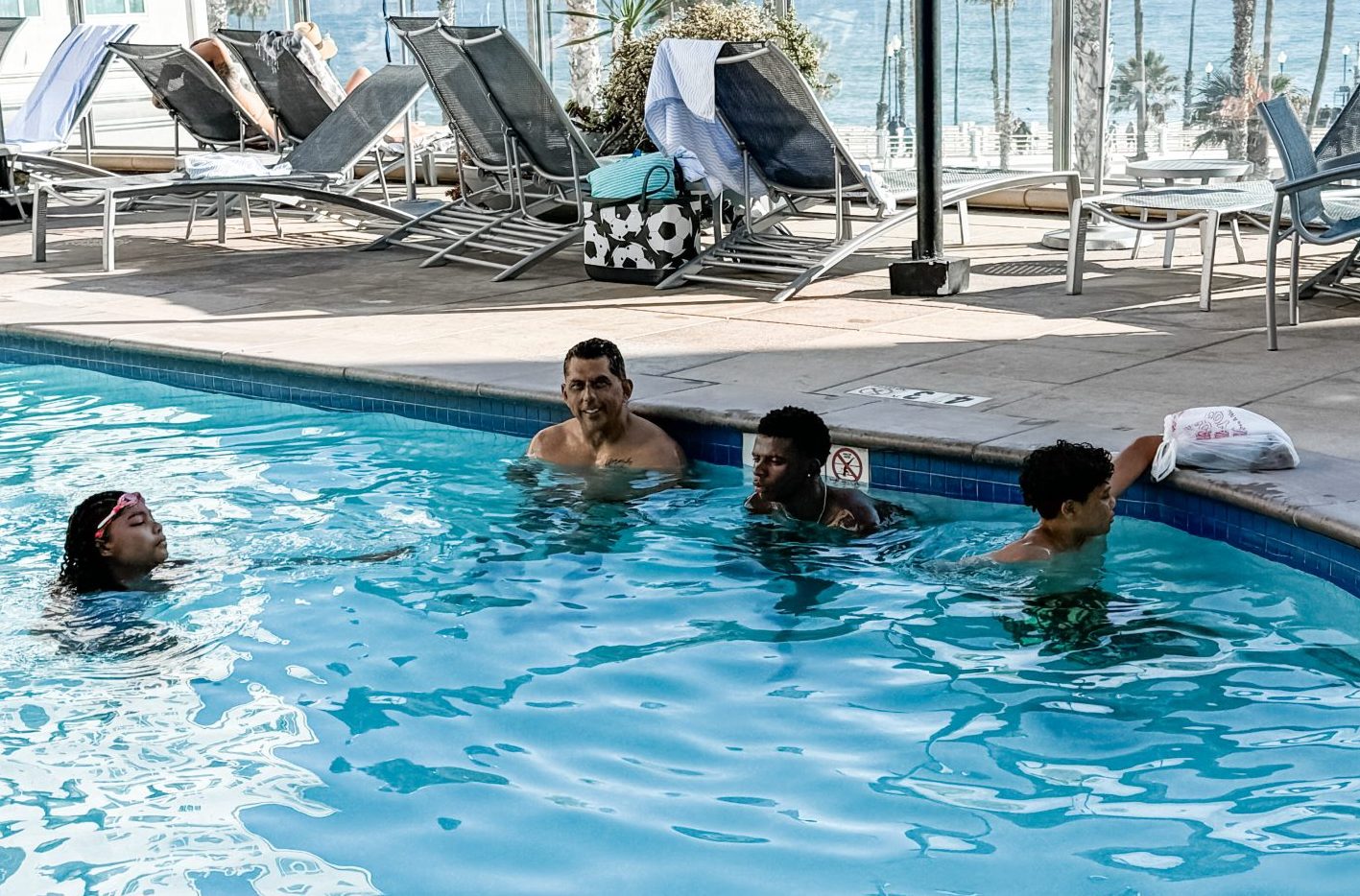 Dad swimming in a hotel pool with three of the kids on a summer day