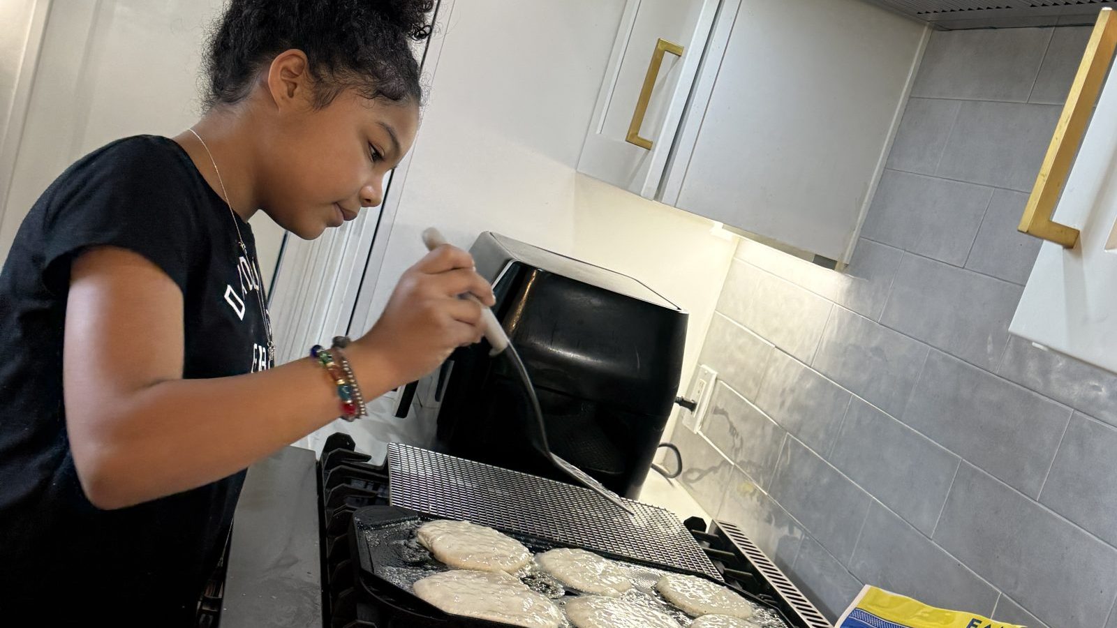 Kaia flipping pancakes on the stove during a slow summer morning